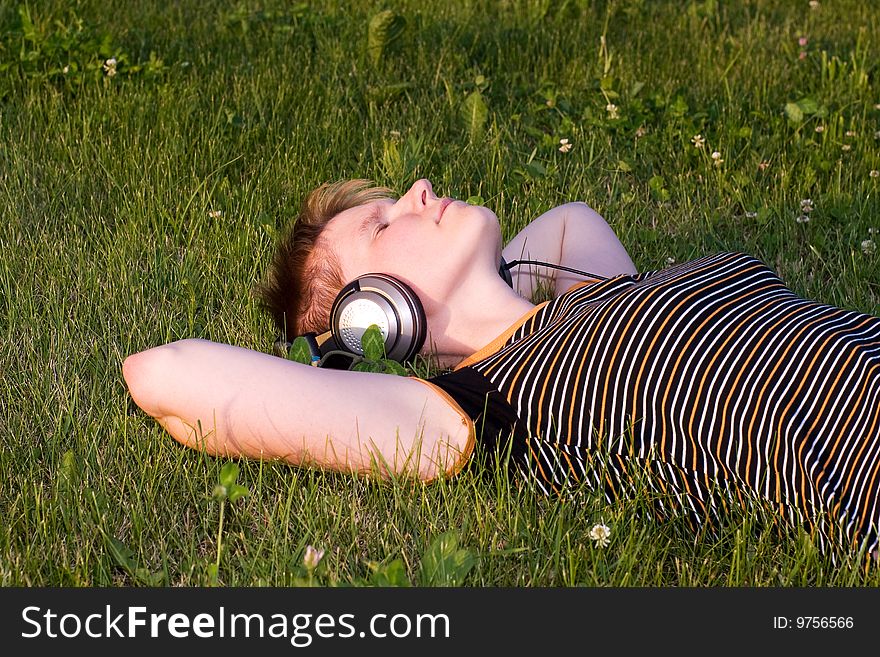 Teenager on a fresh green grass listening music. Teenager on a fresh green grass listening music