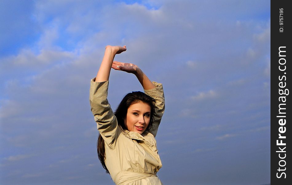 Young nice woman with lifted hands on background of blue sky. Young nice woman with lifted hands on background of blue sky