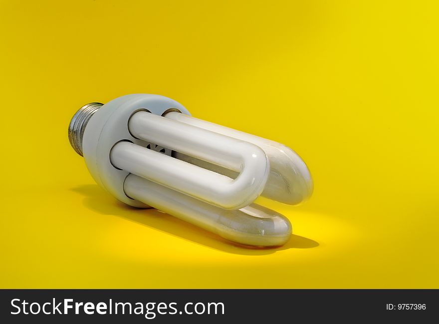 New energy: energy saving bulb under light spot on yellow