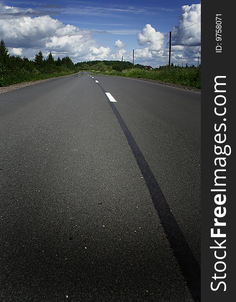 Green grass, the blue sky and white clouds and road