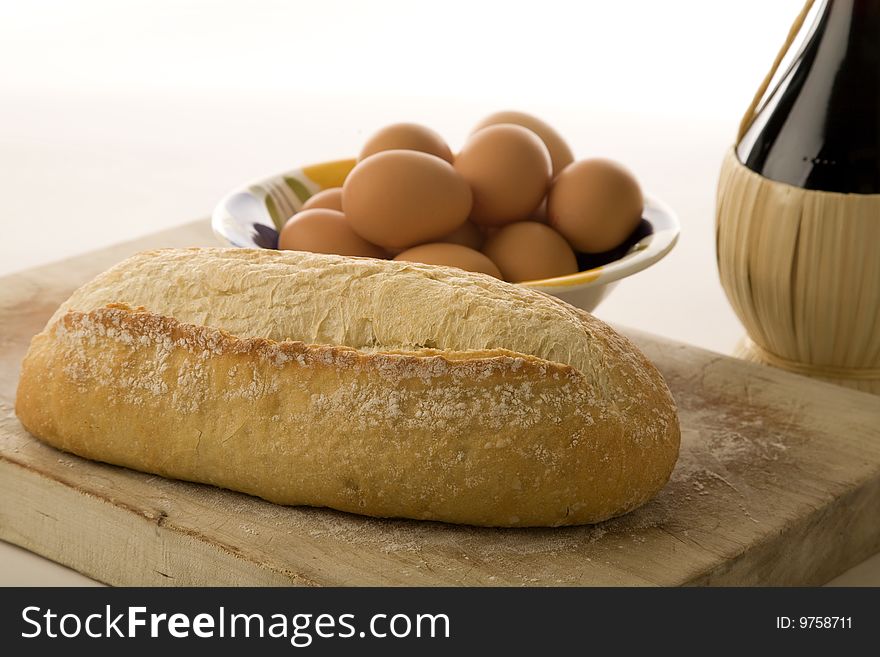 Italian artisan bread on cutting board with eggs and wine. Italian artisan bread on cutting board with eggs and wine.