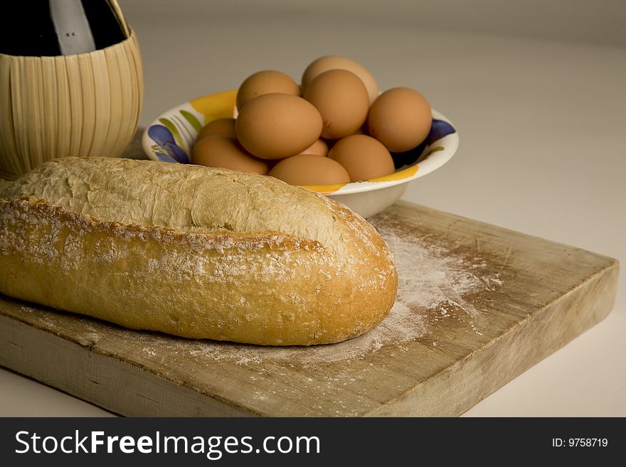 Italian artisan bread on cutting board with eggs and wine. Italian artisan bread on cutting board with eggs and wine.