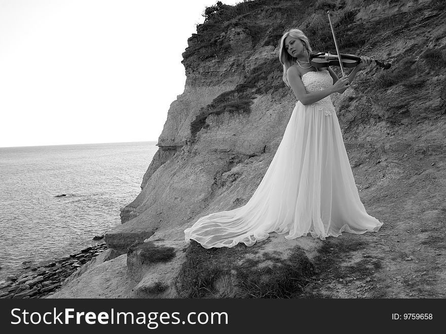 Bride playing with violin by the sea. Bride playing with violin by the sea