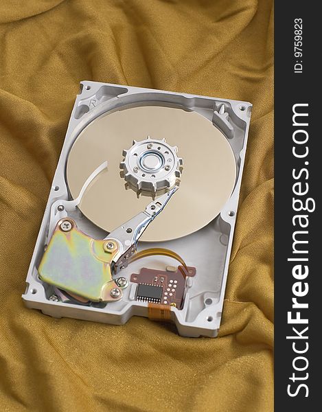 Open harddisk on golden fabric background