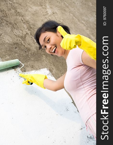 Cheerful asian young woman looks satisfied with her painting work so far. give thumbs up and smiling. Cheerful asian young woman looks satisfied with her painting work so far. give thumbs up and smiling.