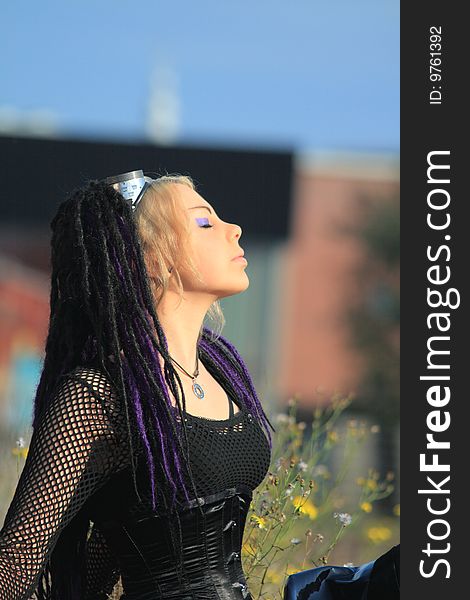 Portrait of a gothic girl wearing a black corset with her head up and eyes closed. Enjoying the sun. Portrait of a gothic girl wearing a black corset with her head up and eyes closed. Enjoying the sun.