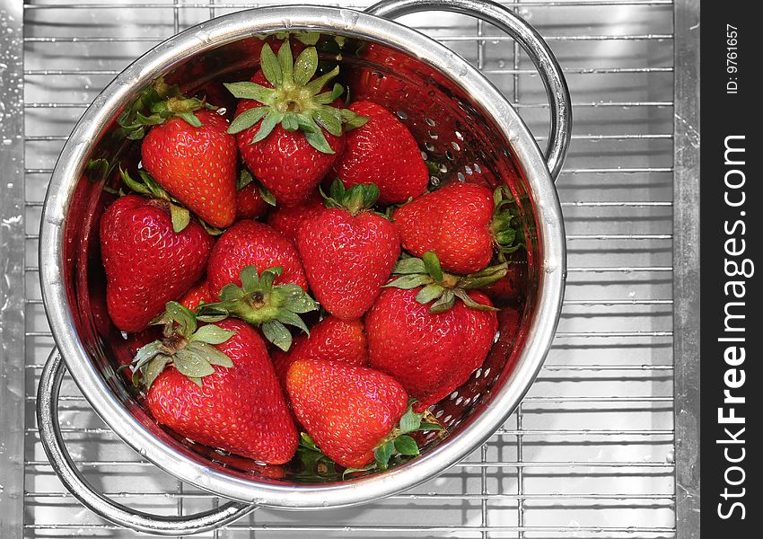 Freshly rinsed strawberries in a stainless steel strainer.