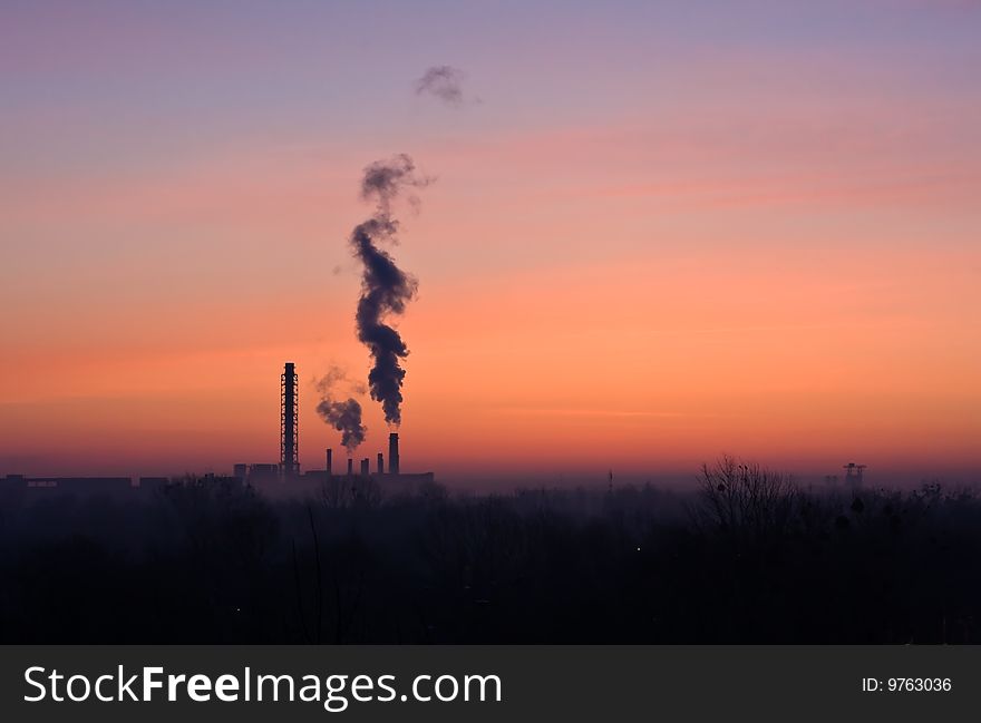A  sunrise with factory silhouettes and a dark cloud. A  sunrise with factory silhouettes and a dark cloud.