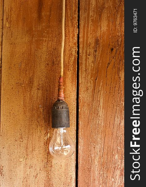 Hanging single lamp against old wooden board. Hanging single lamp against old wooden board