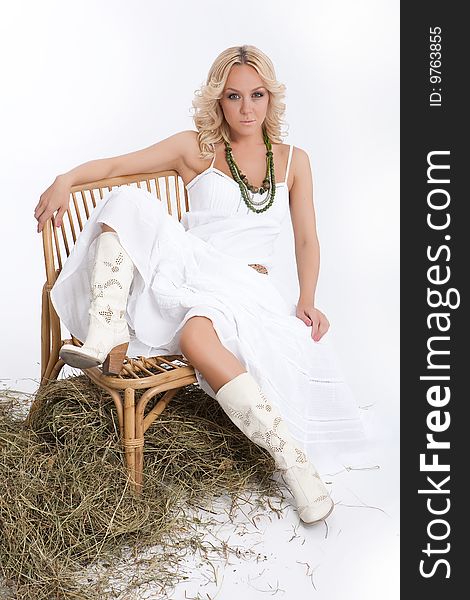 Young blonde woman in a white dress and cowboy boots. Young blonde woman in a white dress and cowboy boots