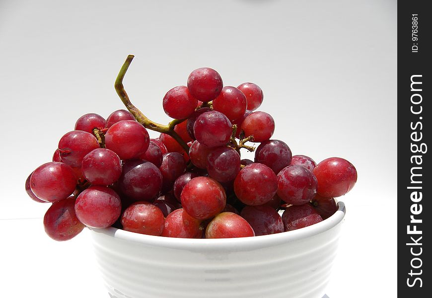 Fresh grapes in a white bowl against a white background