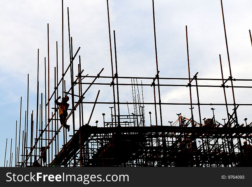 The workers on scaffolds under the blue sky.