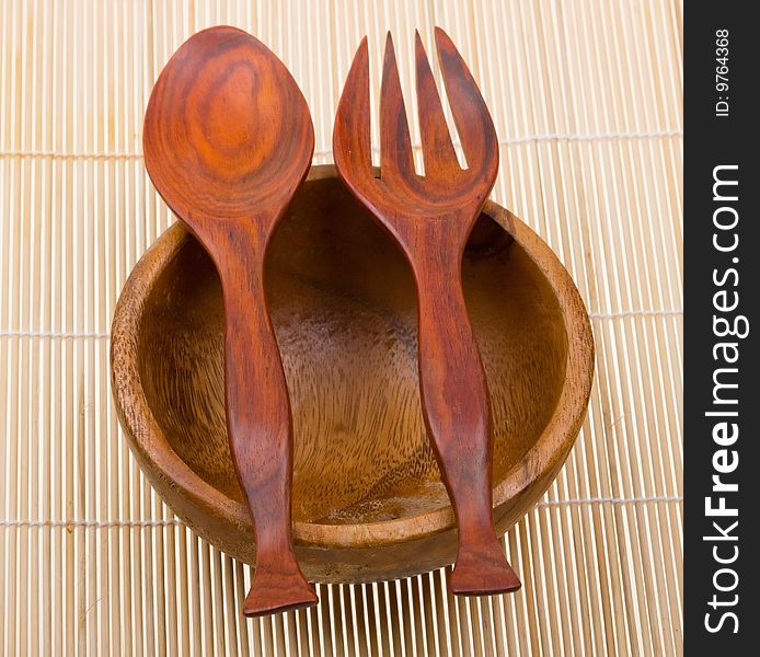 Wooden spoon, fork and basin on bamboo mat