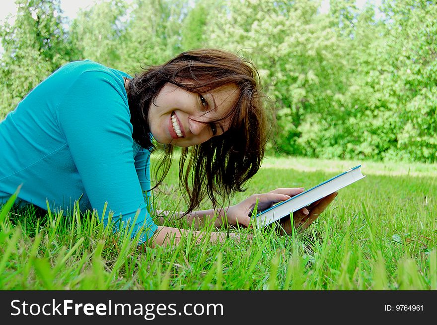Young beautiful woman lays on green field