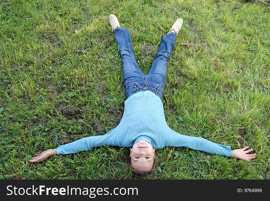 The girl lays on a  green grass