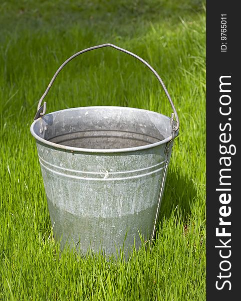 Old bucket stands on green grass. Old bucket stands on green grass