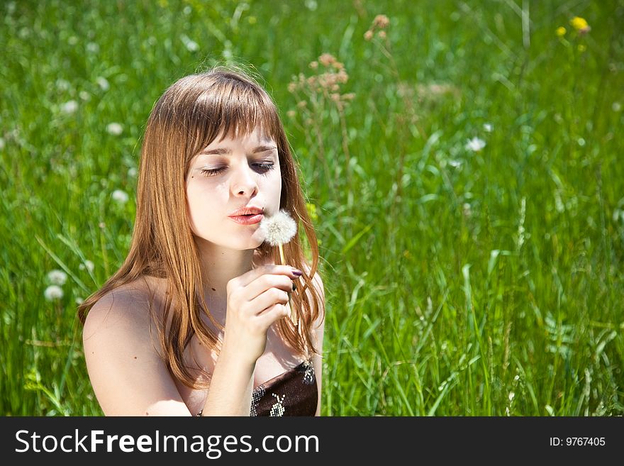 Young girl blowing on dandelion