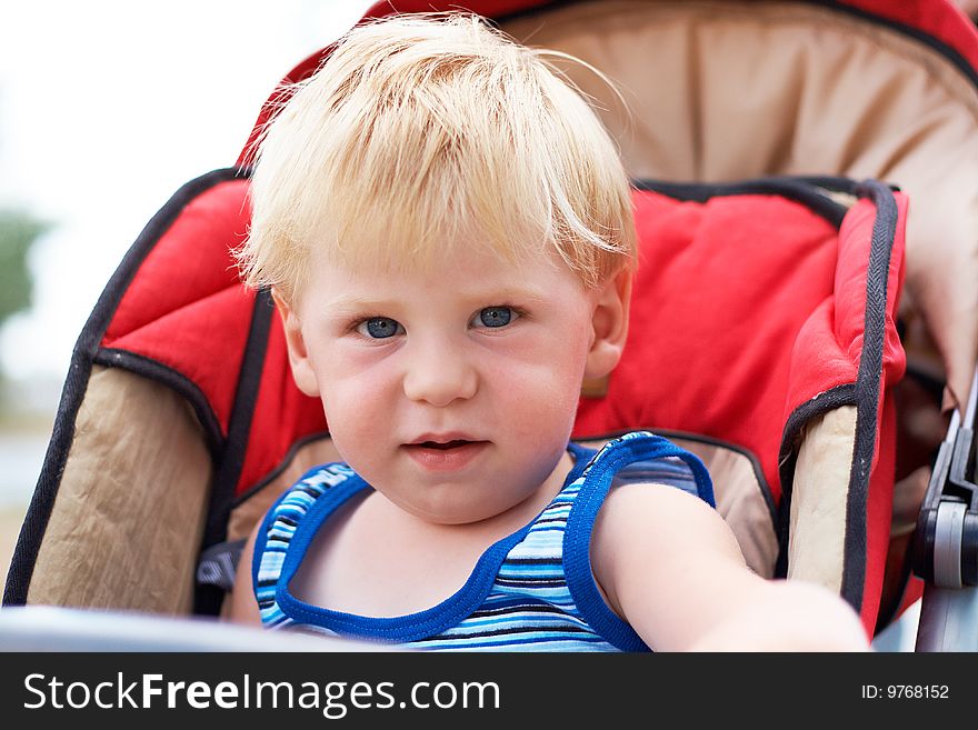 The Little Boy Sits In A Children S Carriage