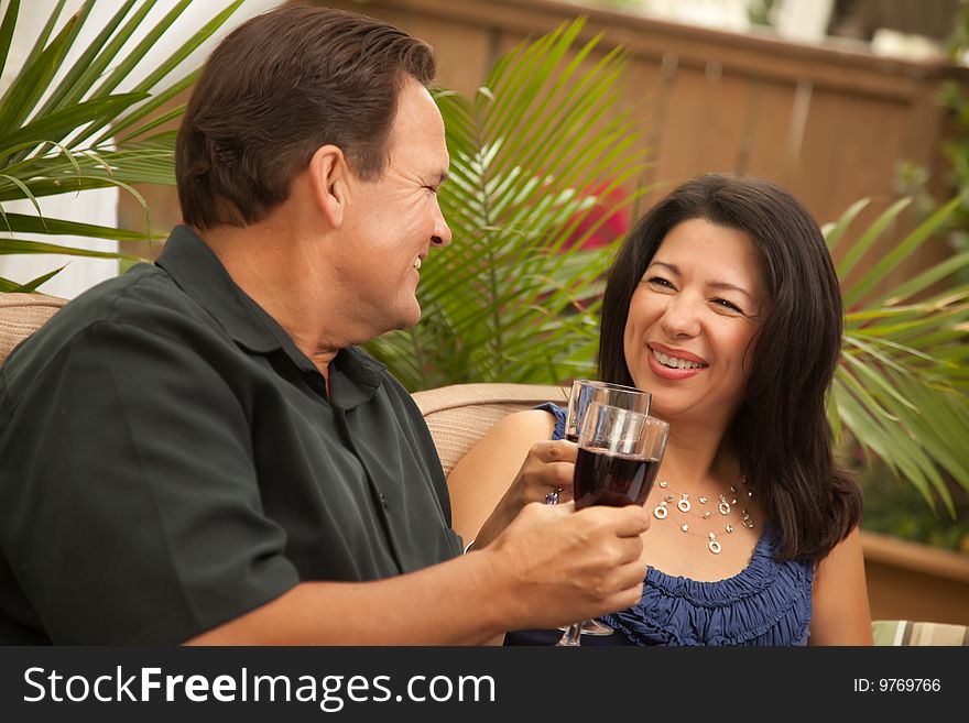 Attractive Hispanic and Caucasian Couple Drinking Wine Outside.