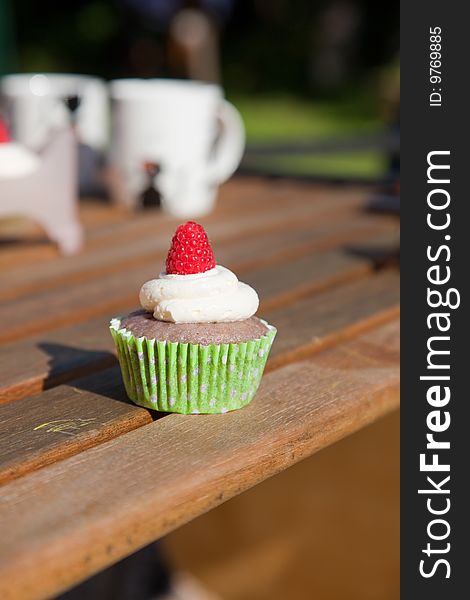 Raspberry cream cupcake on picnnic table. Raspberry cream cupcake on picnnic table.