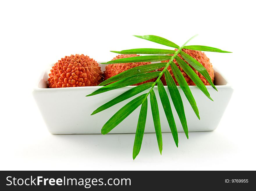 Three lychee and a green leaf in a dish with clipping on a white background. Three lychee and a green leaf in a dish with clipping on a white background
