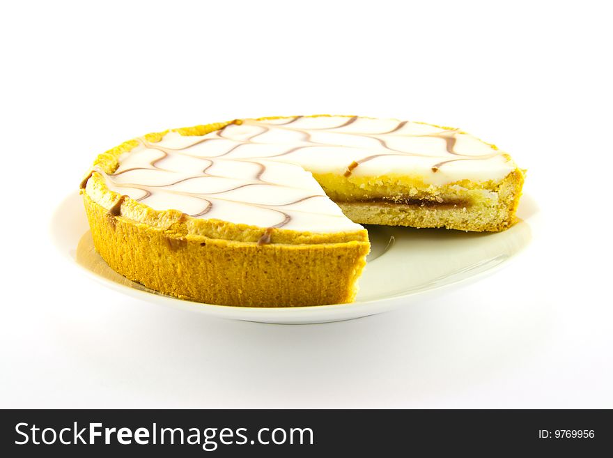 Delicious looking iced bakewell tart on a white plate with a plain background