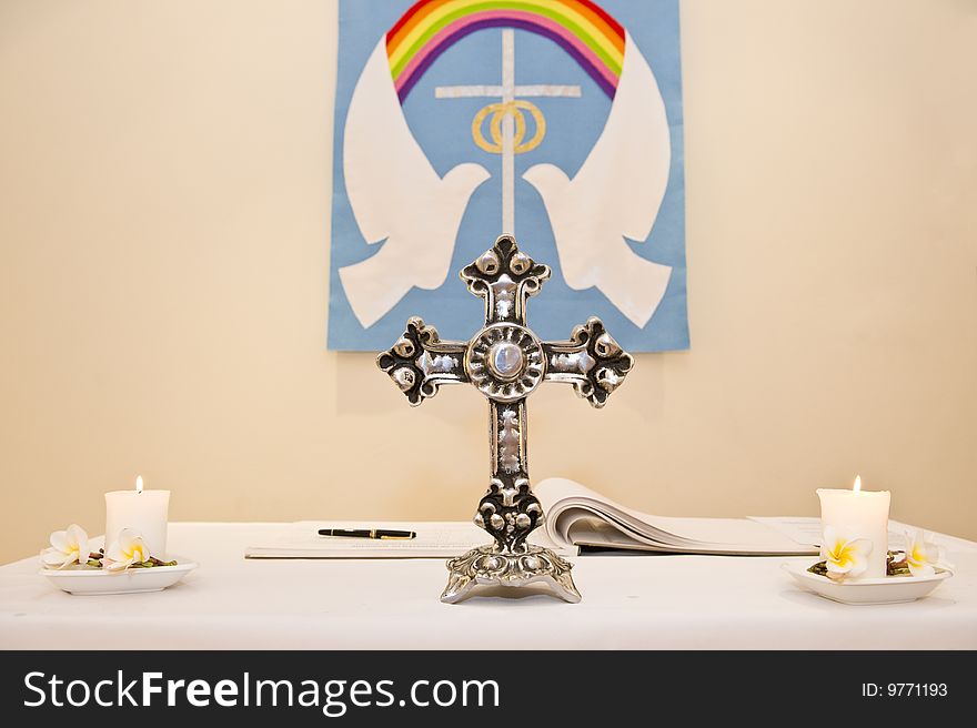 A Christian church pulpit with a cross and two candles.  The doves of peace is on a sign on the wall.