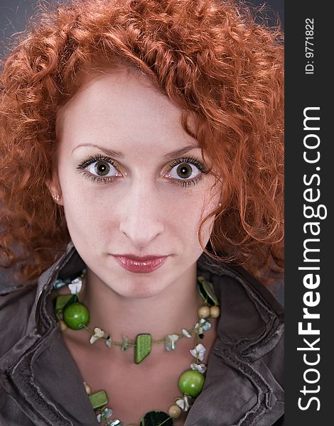 Beautiful model with curly red hair on gray background.
