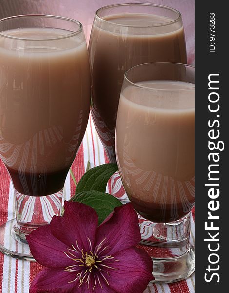 Three chocolate sodas with chocolate syrup on the bottom of glasses and made with ice milk