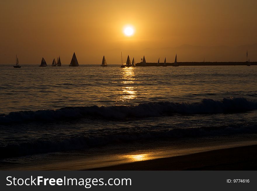 Several sailboats sail through the sunset and reflection. Several sailboats sail through the sunset and reflection