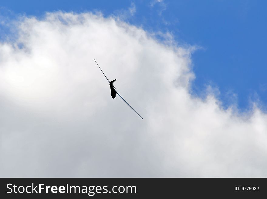 A sailplane against blue sky with white summer clouds