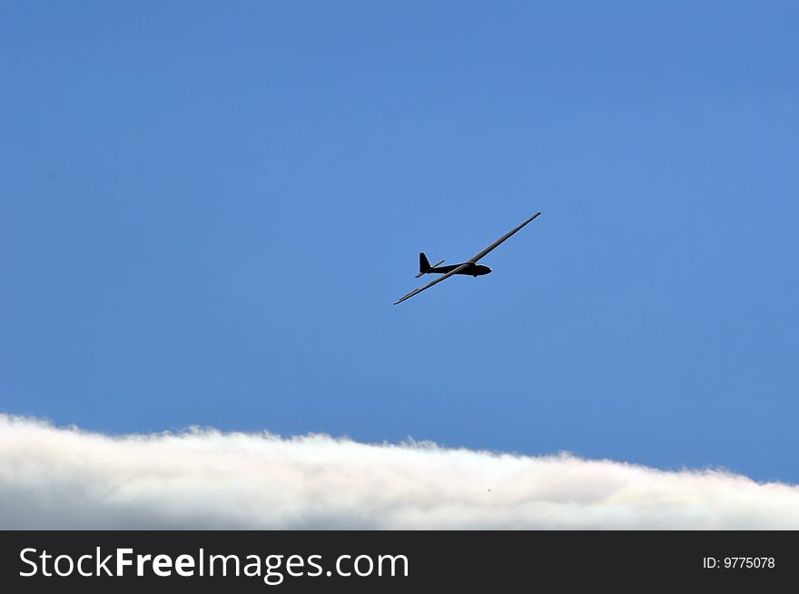 A sailplane against blue sky with white summer clouds