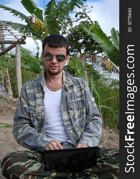 The young man with the computer and its new workplace in jungle