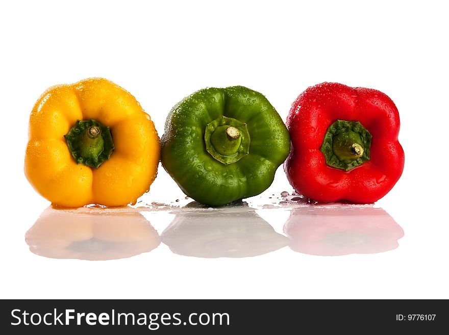 Three fresh peppers under pouring water isolated over a white background