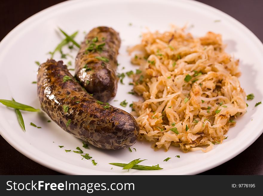 Two grilled bavarian sausage with cabbage, closeup studio shot