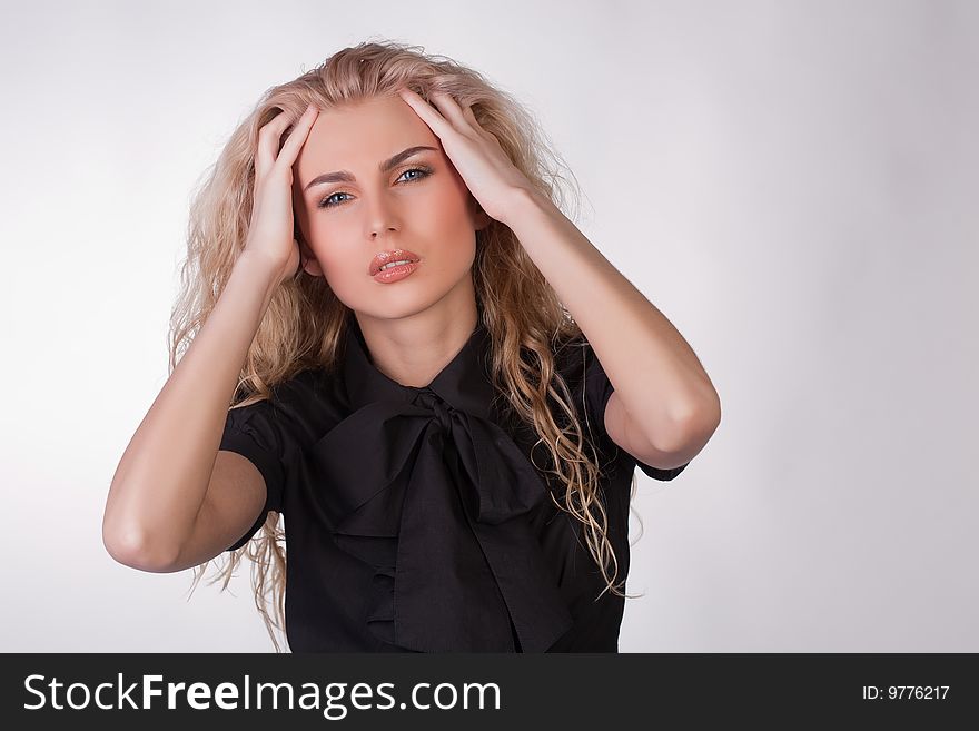 Blond young woman with a pounding headache, studio shot