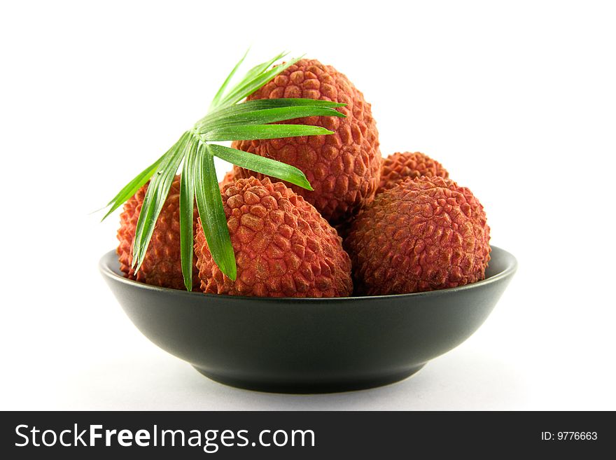 Group of lychee and green leaf in a black dish with clipping and a white background. Group of lychee and green leaf in a black dish with clipping and a white background