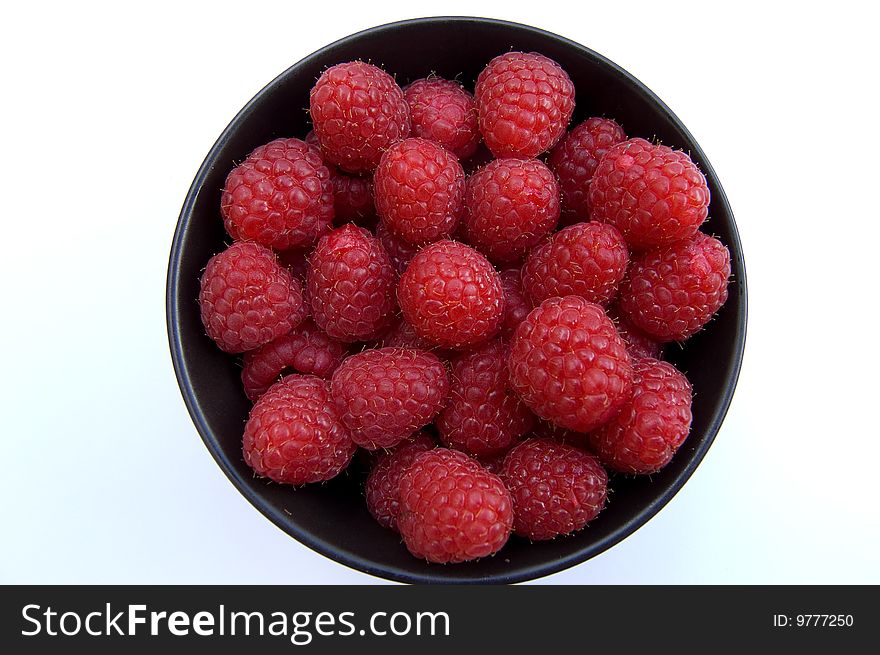 Overhead shot of fresh red raspberries in black bowl on white background. Overhead shot of fresh red raspberries in black bowl on white background