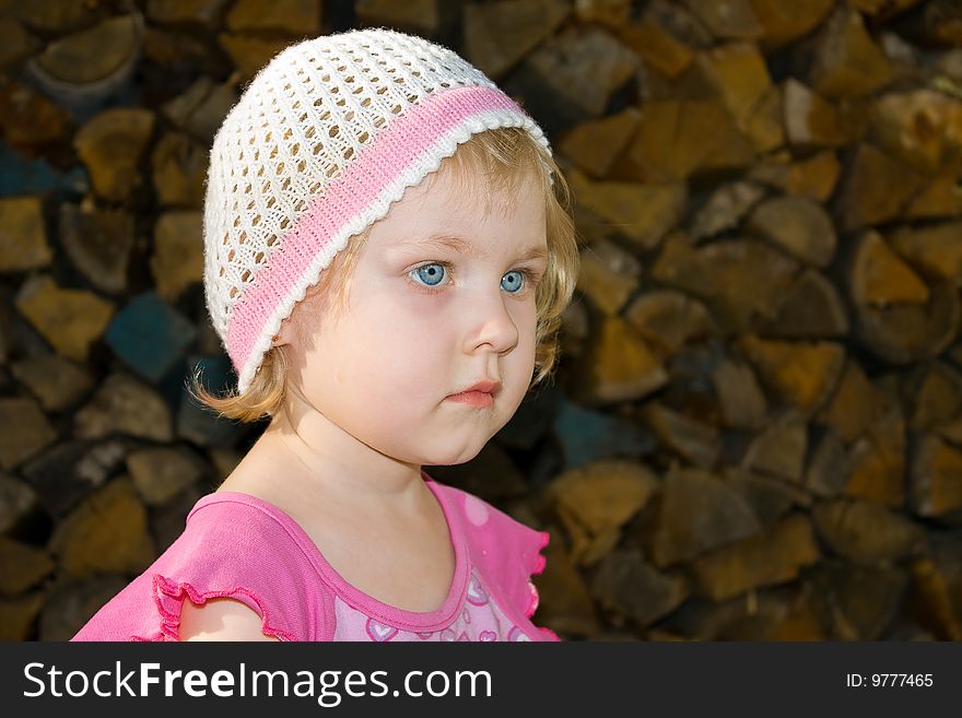 Little girl sits against fire wood. Little girl sits against fire wood