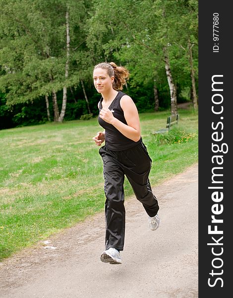 Sportive young woman running over a forrest road