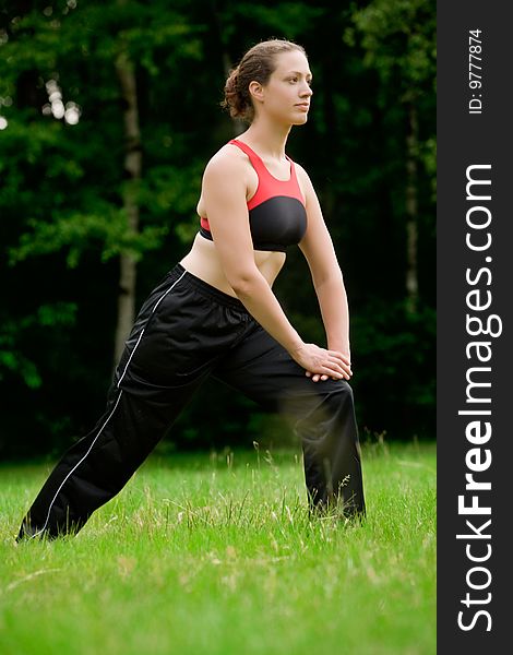 Practising Yoga In A Green Field With Trees