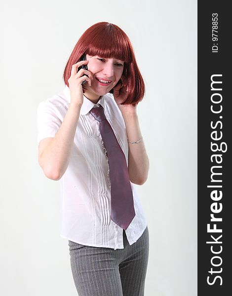 The business woman speaks a mobile phone on a grey background. The business woman speaks a mobile phone on a grey background