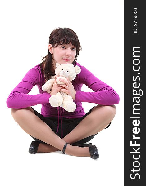 The girl sits on a floor with a toy on a white background