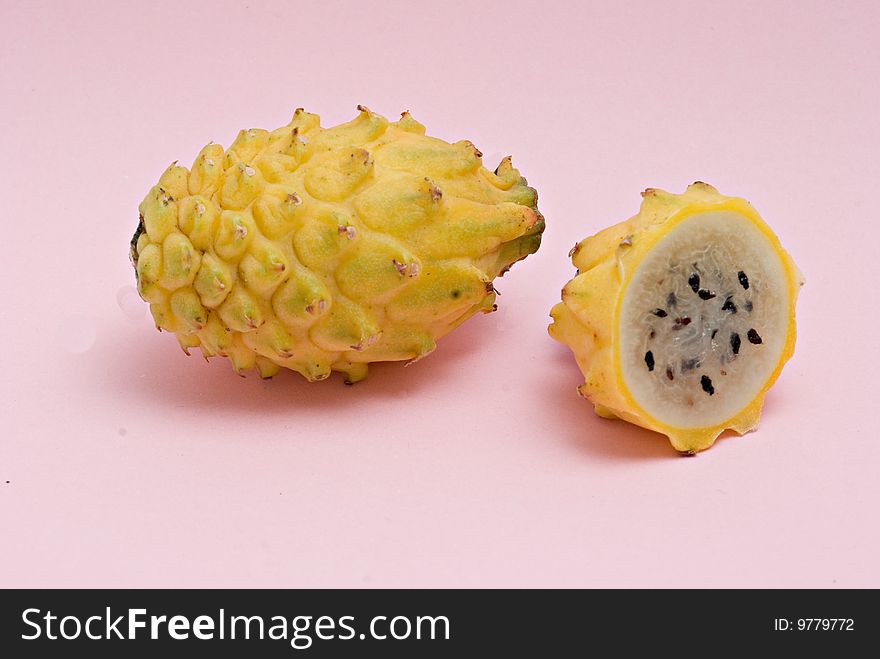 Yellow dragon fruit and its section isolated on pink background