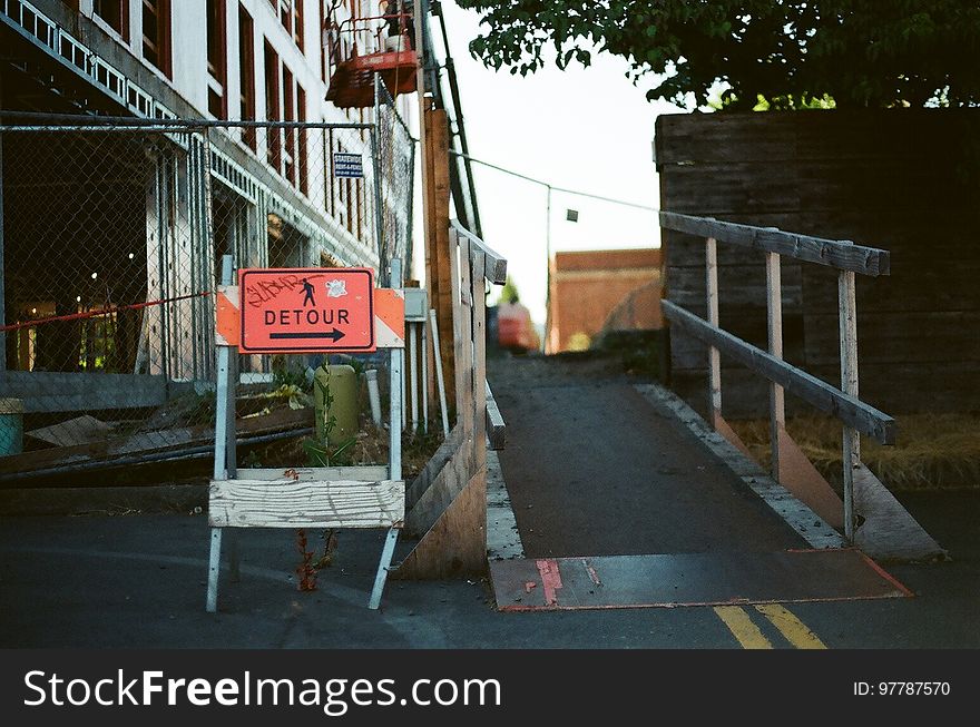 A construction site with a sign pointing to a a detour around it.