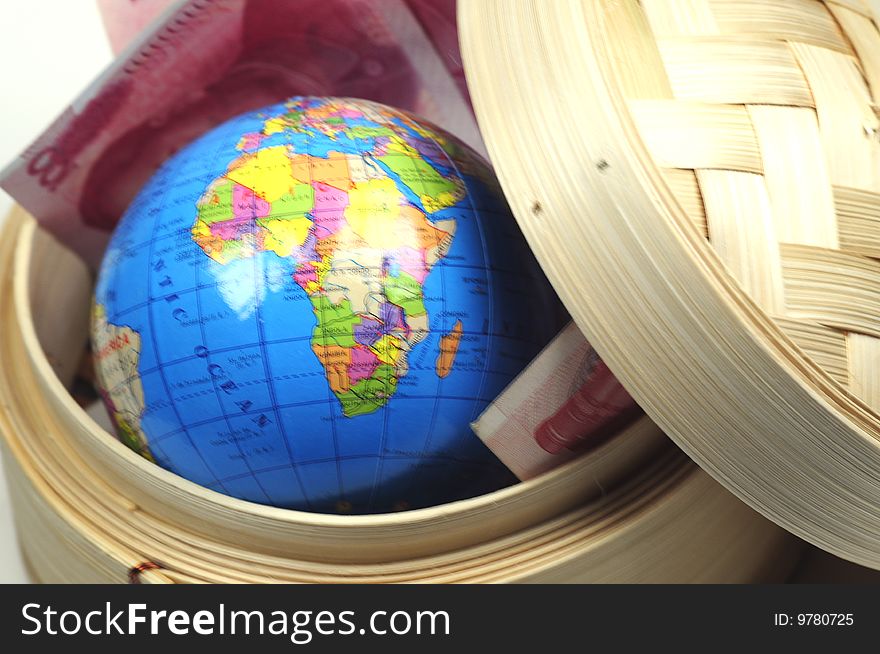 A globe and some chinese currency in a dim sum basket. A globe and some chinese currency in a dim sum basket