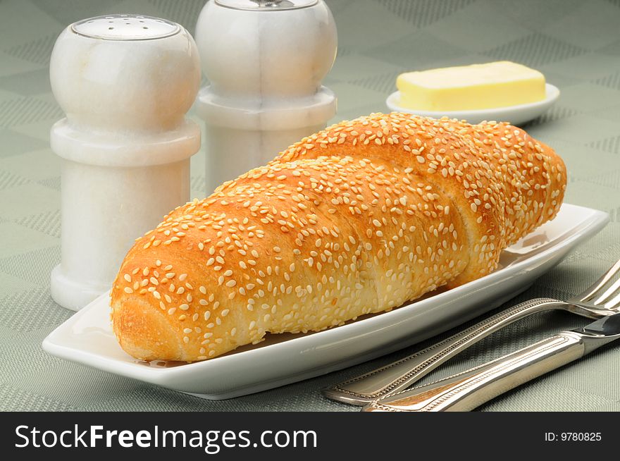 Fresh baked sesame seed dinner roll and butter.