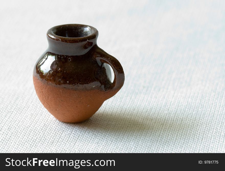 Orange clay ceramic pot, shaped rounder at the bottom, and more narrow at the top with a handle.  Isolated on white background.