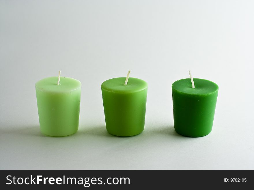 Three scented candles in varying shades of green.