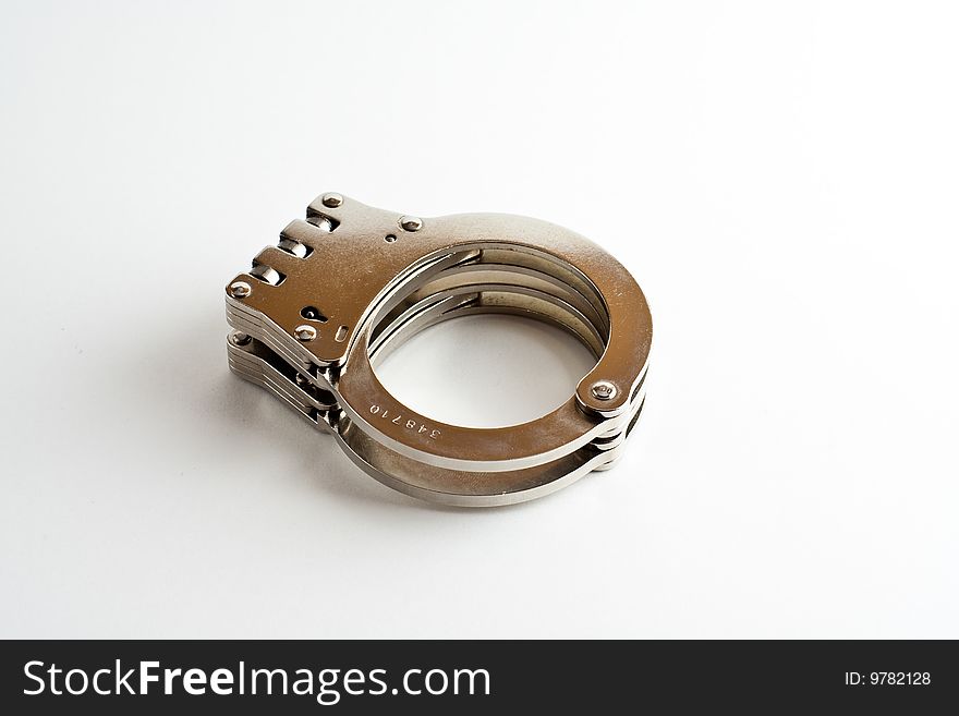 A pair of hinged handcuffs isolated on a white background.